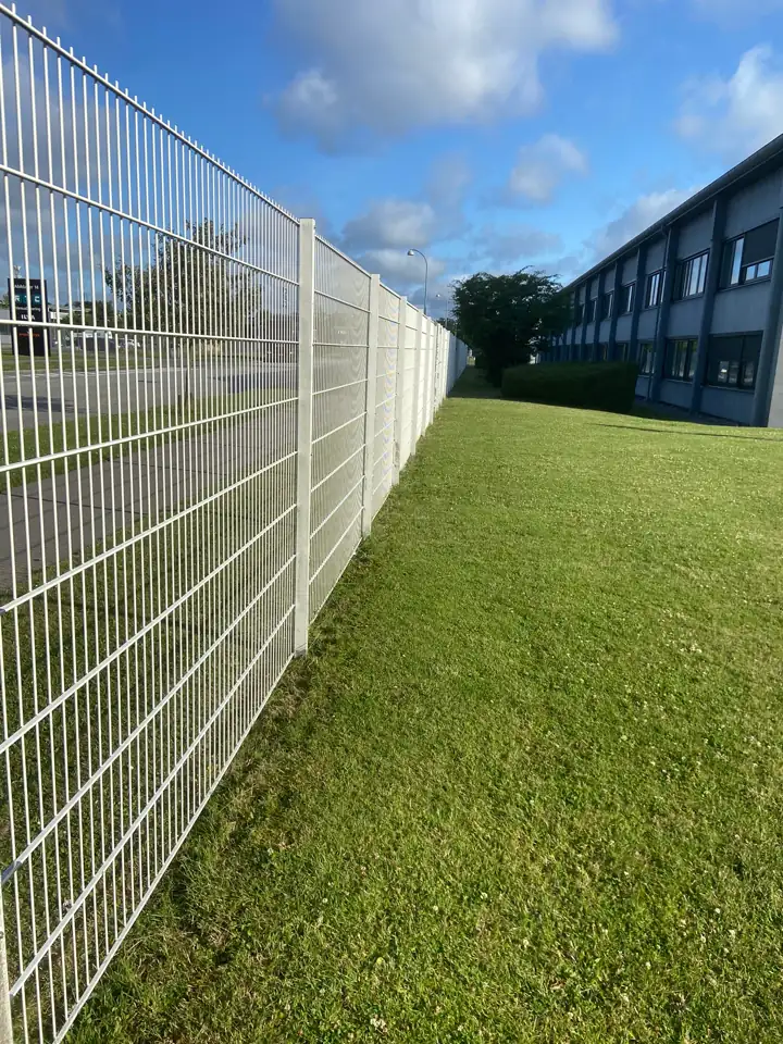 Græsareal langs hegnet ved en erhvervsejendom